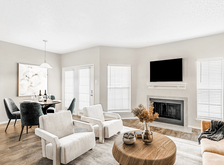 Virtually staged livingroom with wood style flooring, accent run, couch with seats, wooden coffee table, dining table with chairs, wall mounted television above fireplace with mantle and windows with blinds